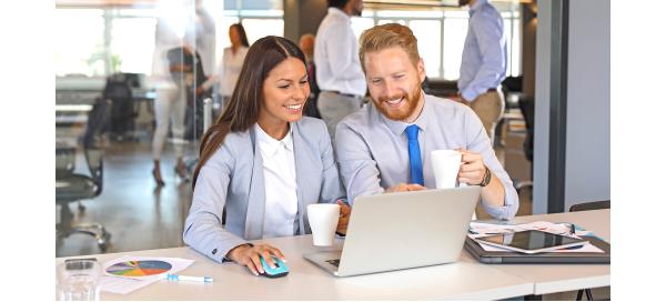 Woman and man holding coffee mugs and smiling over computer