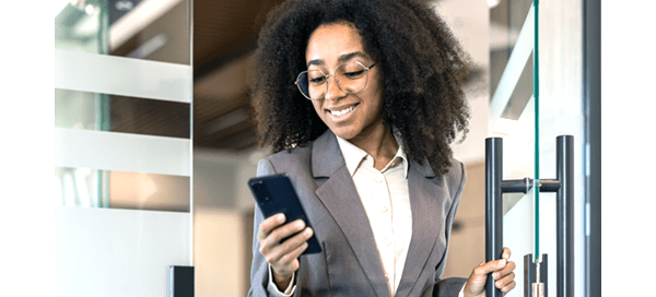 Woman with glasses wearing a suit and smiling at phone