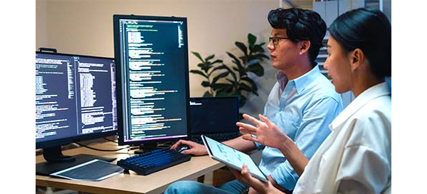 Two engineers looking at coding on computer